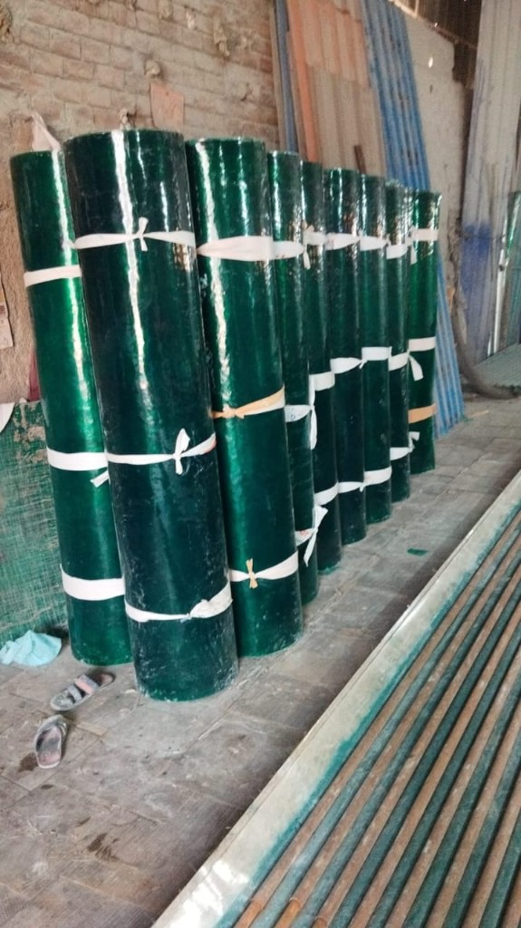 Tall FRP plain sheet rolls stacked vertically inside the shop, showing consistent colour and thickness.