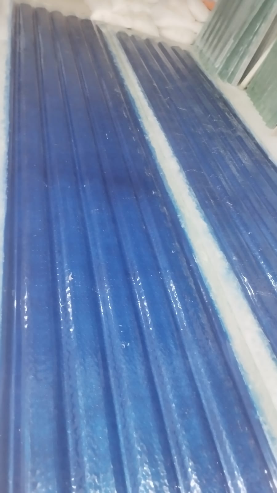 Stack of translucent blue FRP corrugated profile sheets with visible ribbed structure.
