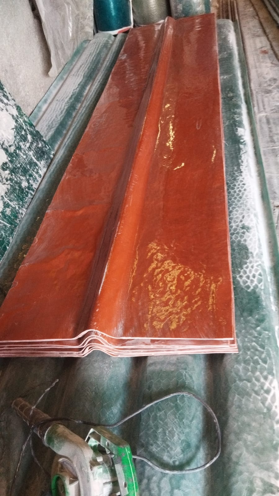 Reddish-brown FRP ridge sheets stacked, showing corrugated ridge profile and glossy finish.