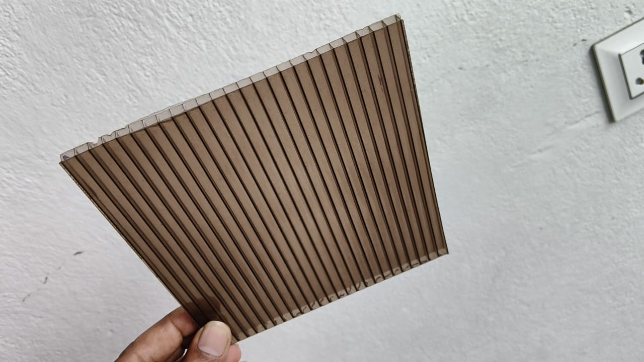 Light bronze multiwall sheet held up, showing channels and translucent finish.